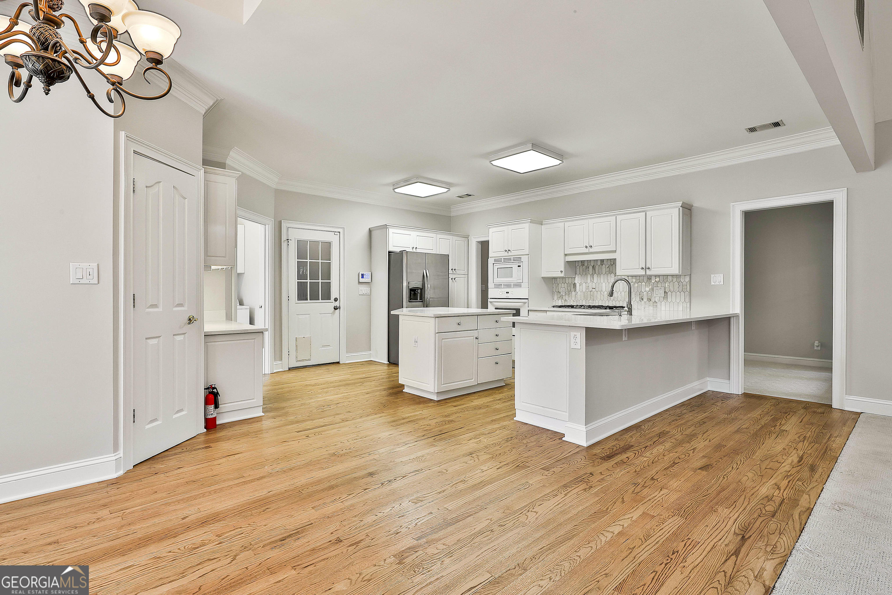 365 Pendleton Trail Tyrone, GA 30290 - Photo 23 of 55 a large white kitchen with kitchen island a sink dishwasher a refrigerator and white cabinets with wooden floor