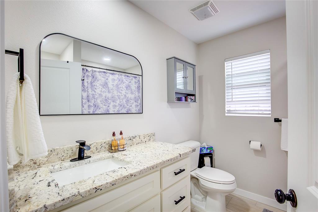 521 Private Road Brookston, TX 75421 - Photo 14 of 26 a bathroom with a granite countertop sink mirror vanity and toilet