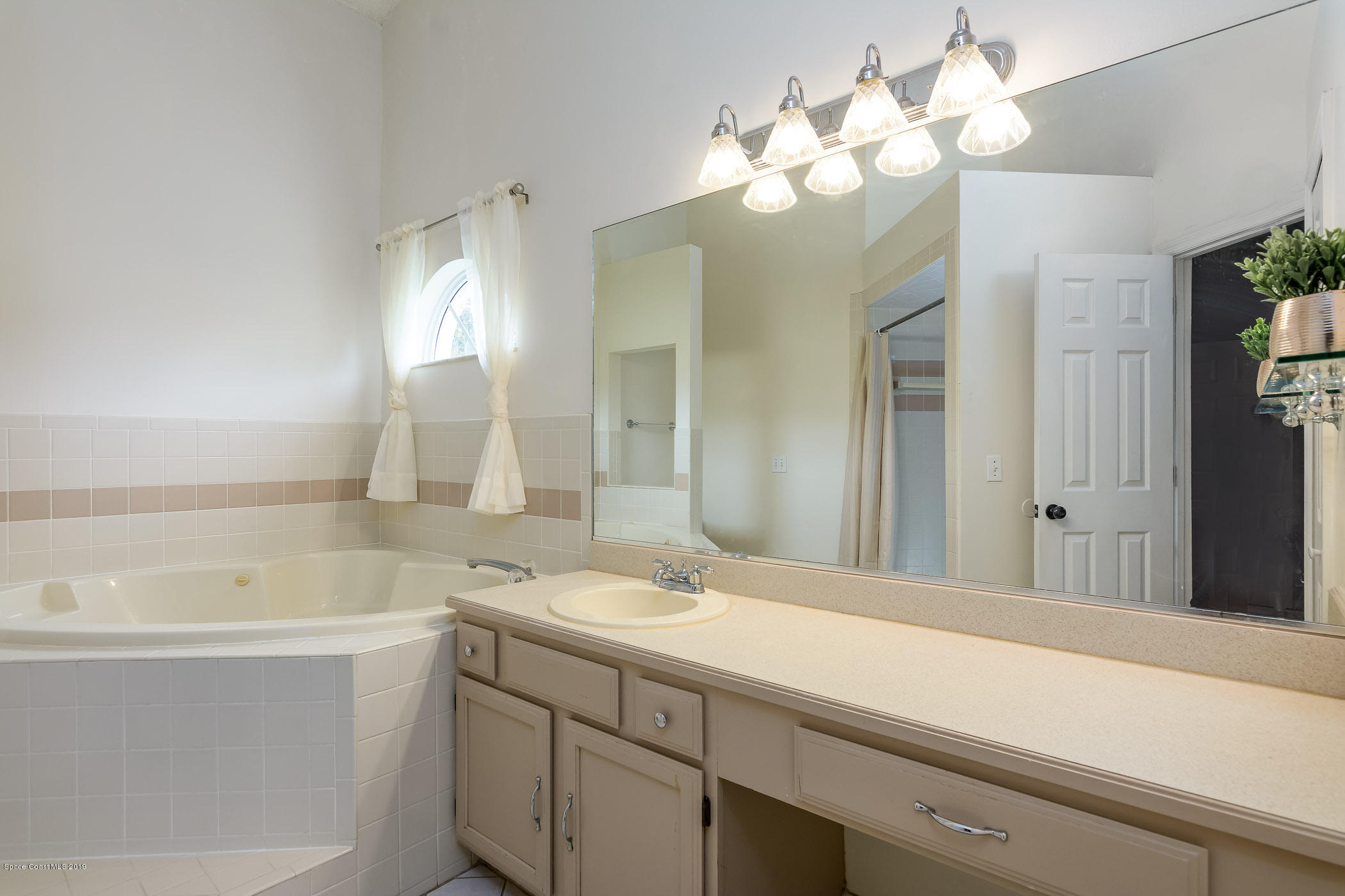 7010 Cairo Road Cocoa, FL 32927 - Photo 16 of 22 a bathroom with a sink a large mirror and a bathtub