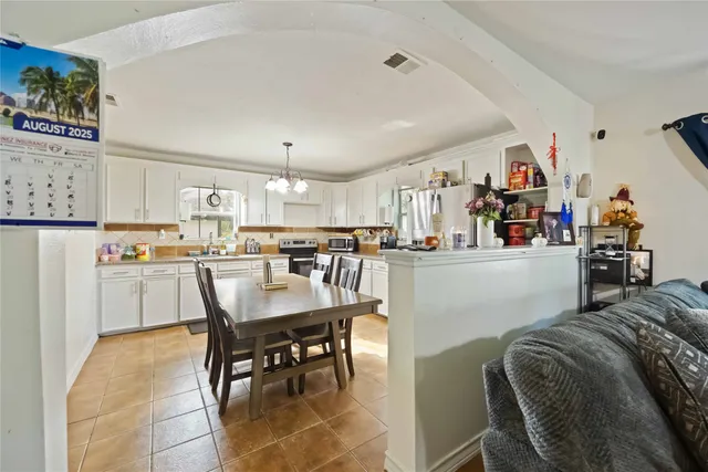 a kitchen with granite countertop a refrigerator a stove a dining table and chairs