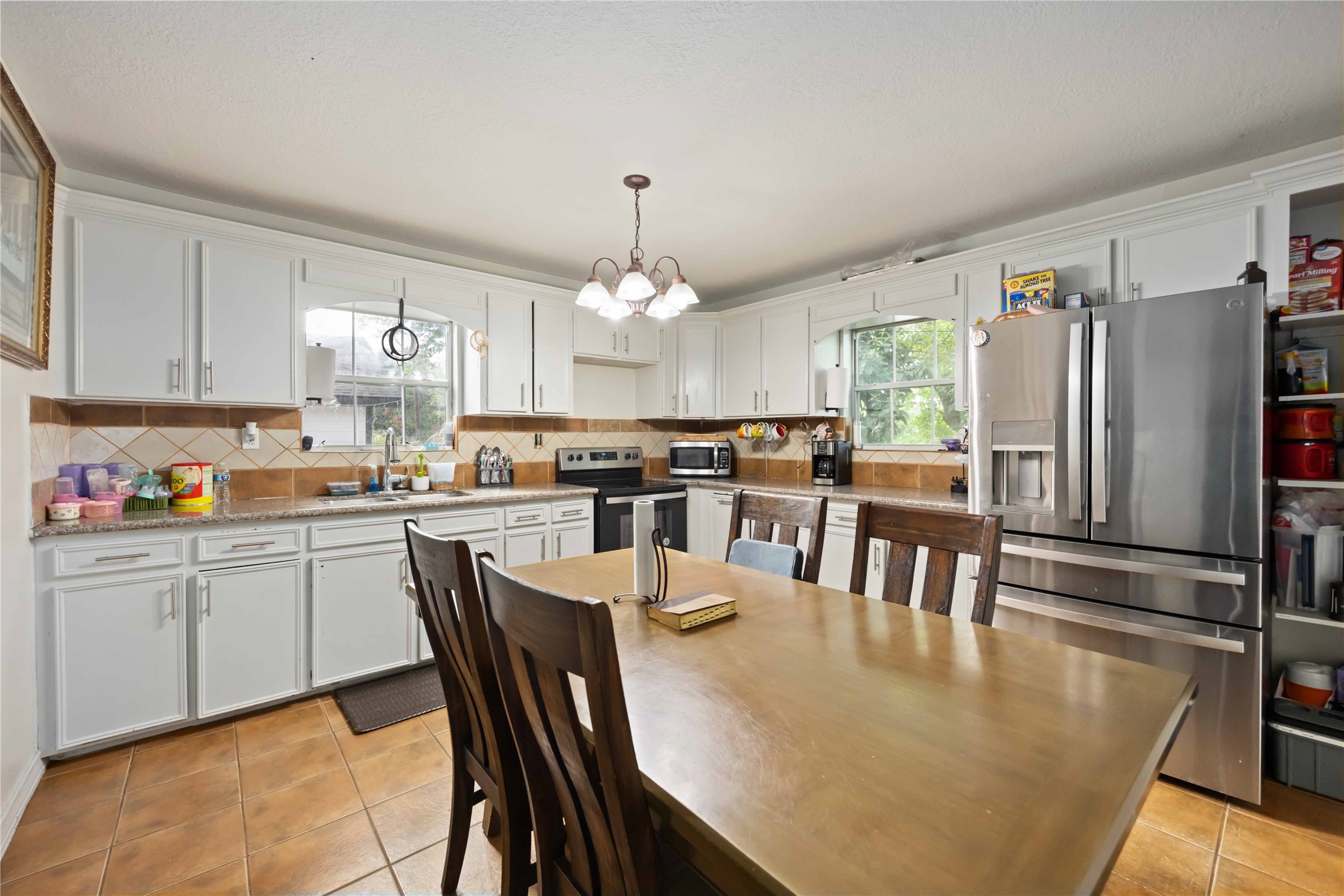 5119 Terry Street Houston, TX 77009 - Photo 10 of 30 a kitchen with granite countertop a refrigerator a stove a dining table and chairs