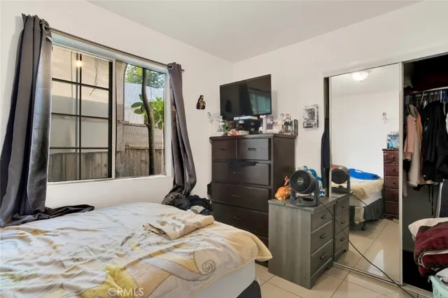 a bedroom with a bed and a flat tv screen on dresser