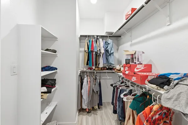 a view of walk in closet with clothes and shoes