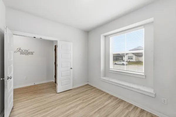an empty room with wooden floor and windows