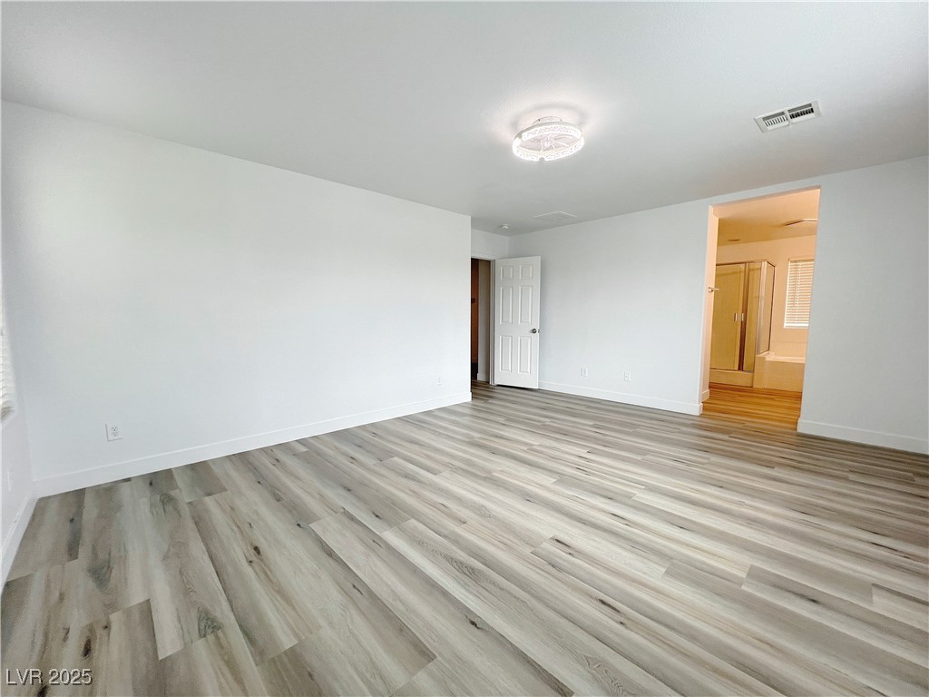 8821 Steaming Thunder Court Las Vegas, NV 89148 - Photo 25 of 31 Unfurnished bedroom with light wood finished floors and connected bathroom