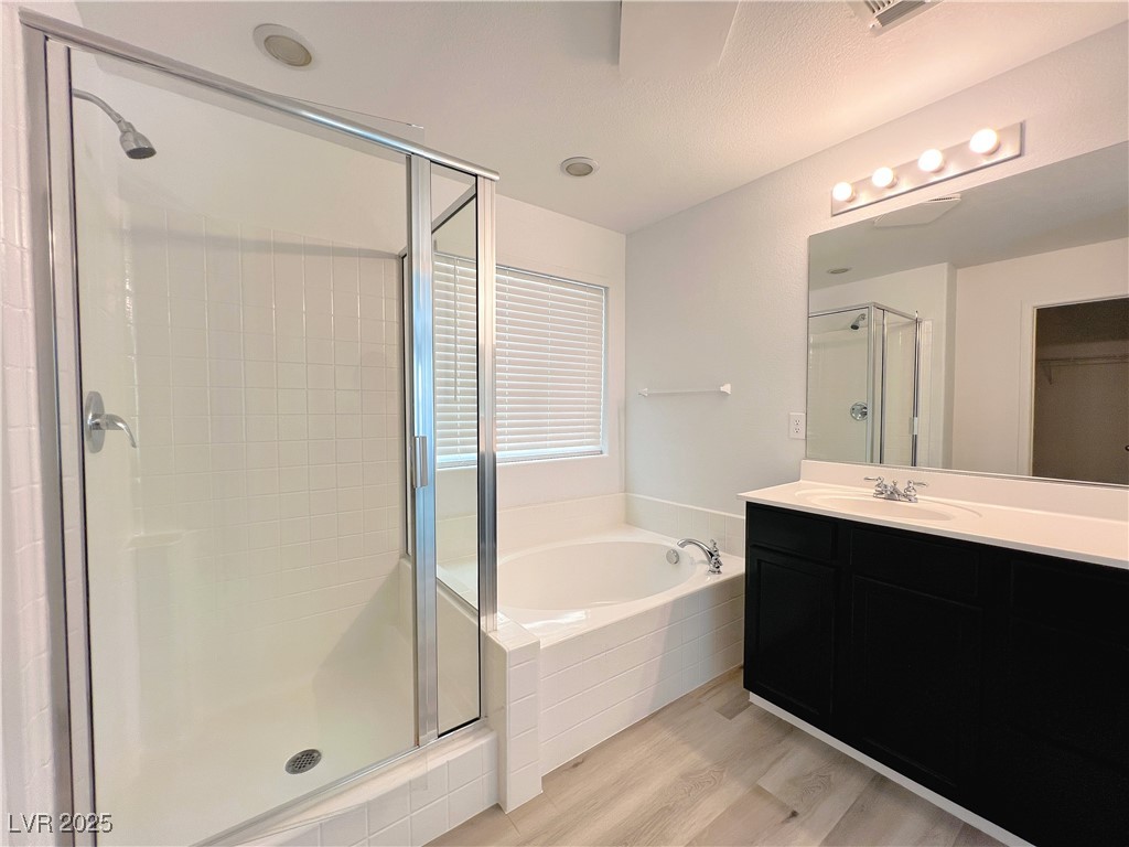 8821 Steaming Thunder Court Las Vegas, NV 89148 - Photo 27 of 31 Bathroom with a shower stall, a bath, vanity, and light wood-type flooring