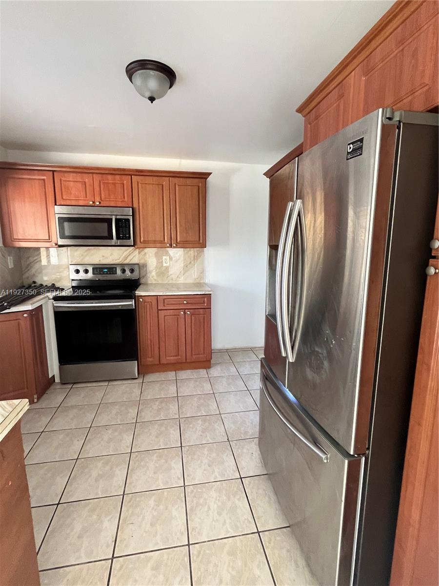 150 Northeast 173rd Street Miami, FL 33162 - Photo 2 of 10 a kitchen with stainless steel appliances granite countertop a refrigerator and a stove top oven