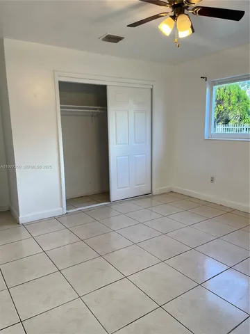 an empty room with windows and ceiling fan