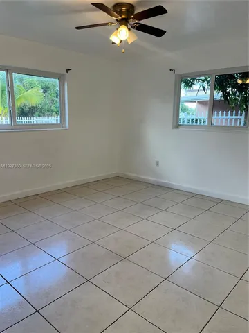 an empty room with windows and ceiling fan