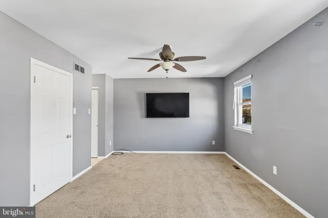 an empty room with ceiling fan and window