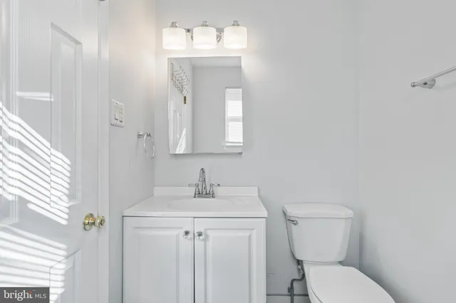a bathroom with a granite countertop toilet a sink a mirror and vanity