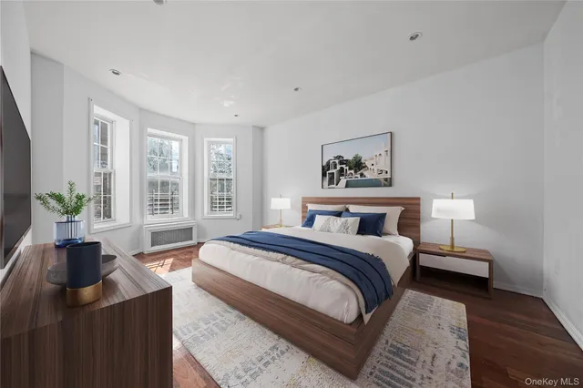 a bedroom with a large bed a potted plant and a window