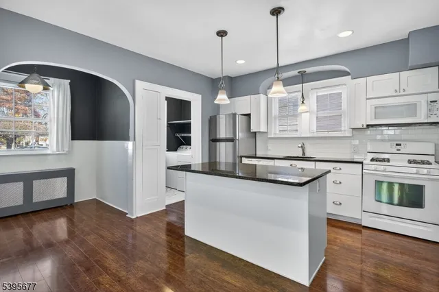 a kitchen with stainless steel appliances granite countertop a sink a stove and a wooden floors