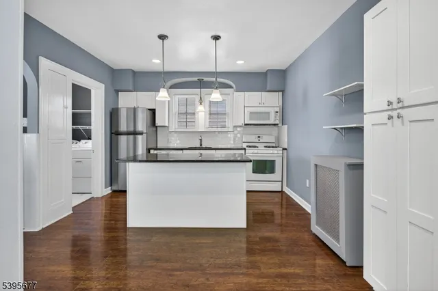 a kitchen with kitchen island white cabinets and stainless steel appliances