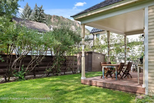a view of a chair and table in backyard of the house