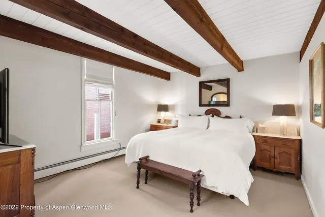 a bedroom with a bed and a flat tv screen on dresser