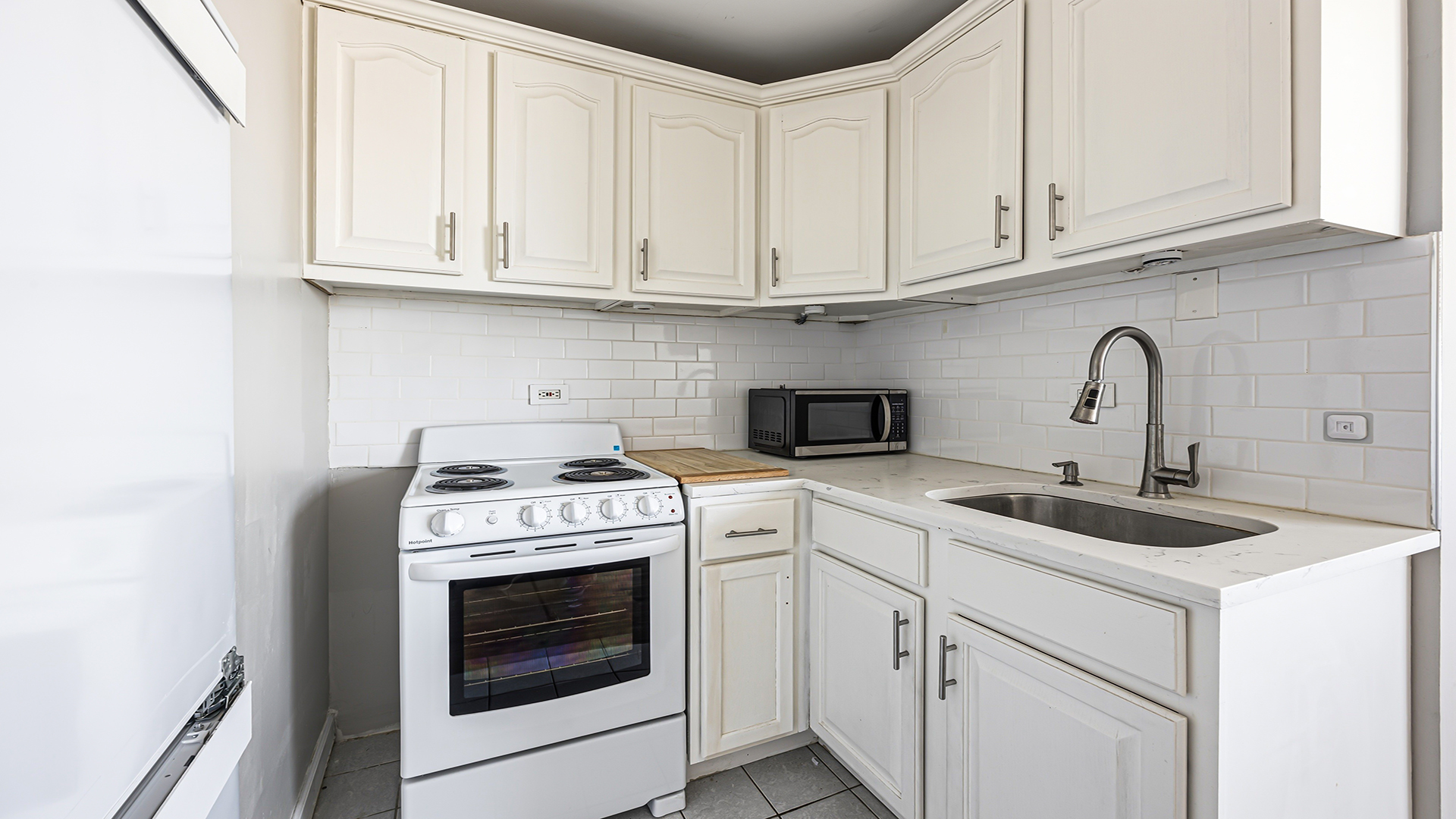 3110 North Sheridan Road, Unit 1807 Chicago, IL 60657 - Photo 11 of 21 a kitchen with white cabinets and white appliances