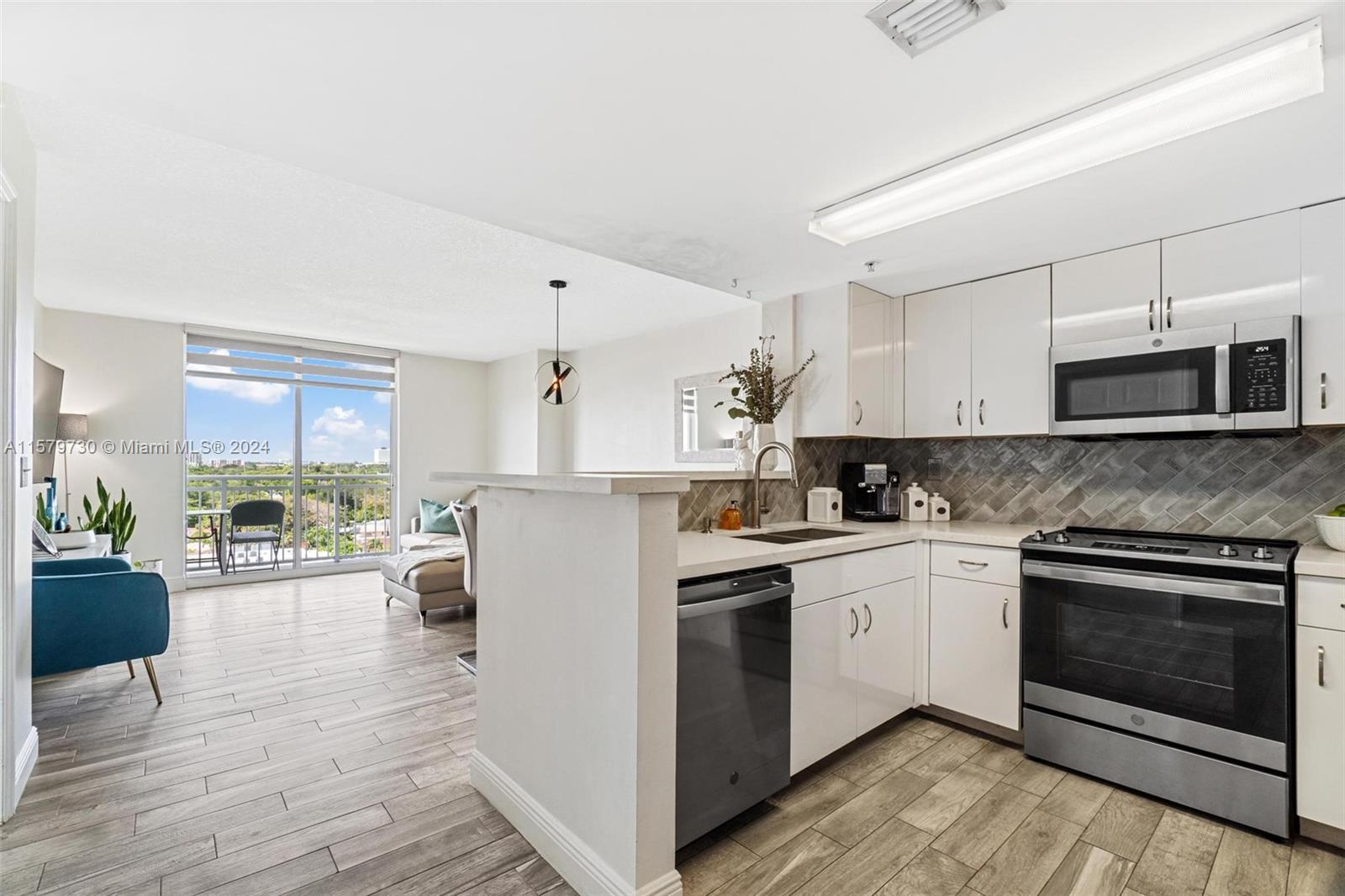 3000 Coral Way, Unit 703 Miami, FL 33145 - Photo 10 of 26 a kitchen with stainless steel appliances granite countertop a stove top oven a sink dishwasher and a refrigerator with wooden floor