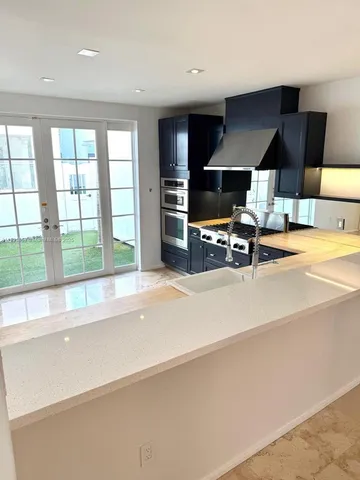 a kitchen with stainless steel appliances a large counter top a stove and a sink with granite countertops