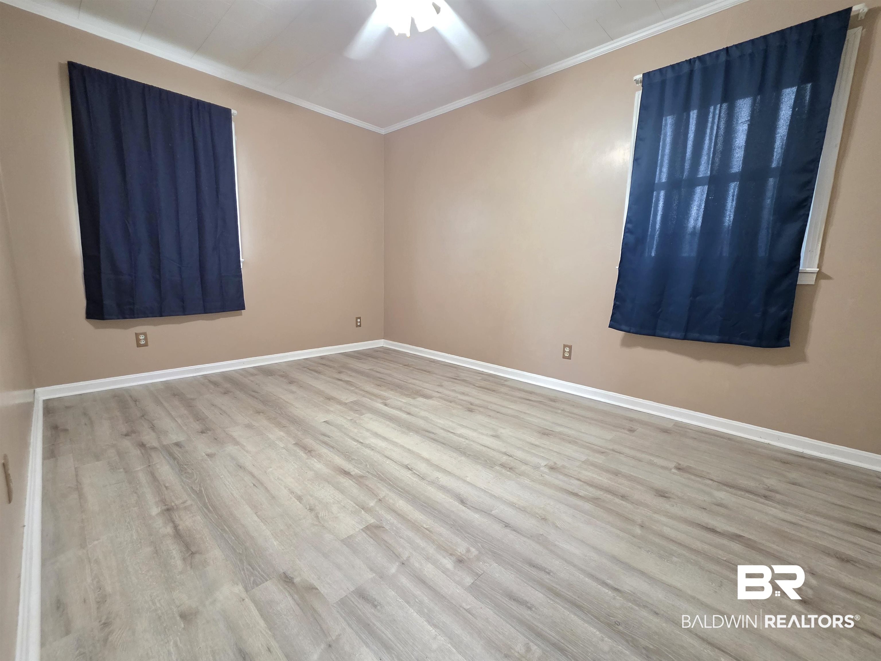 558 Stanton Road Atmore, AL 36502 - Photo 16 of 29 Spacious room featuring wood-finish flooring, neutral-toned walls, white baseboards, and two windows