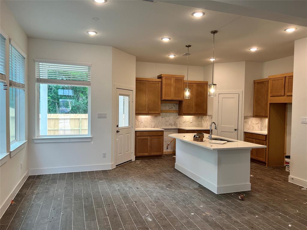 a large kitchen with stainless steel appliances granite countertop a stove a sink dishwasher a refrigerator white cabinets and wooden floor next to a window