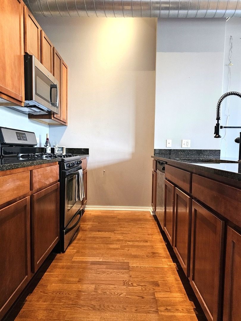 2323 West Pershing Road, Unit 230 Chicago, IL 60609 - Photo 9 of 39 a kitchen with stainless steel appliances granite countertop a sink and a stove top oven