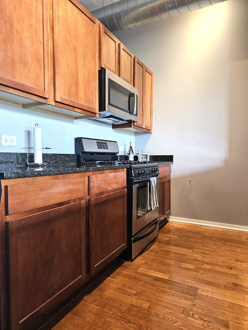 2323 West Pershing Road, Unit 230 Chicago, IL 60609 - Photo 10 of 39 a kitchen with stainless steel appliances granite countertop a stove a sink and a microwave