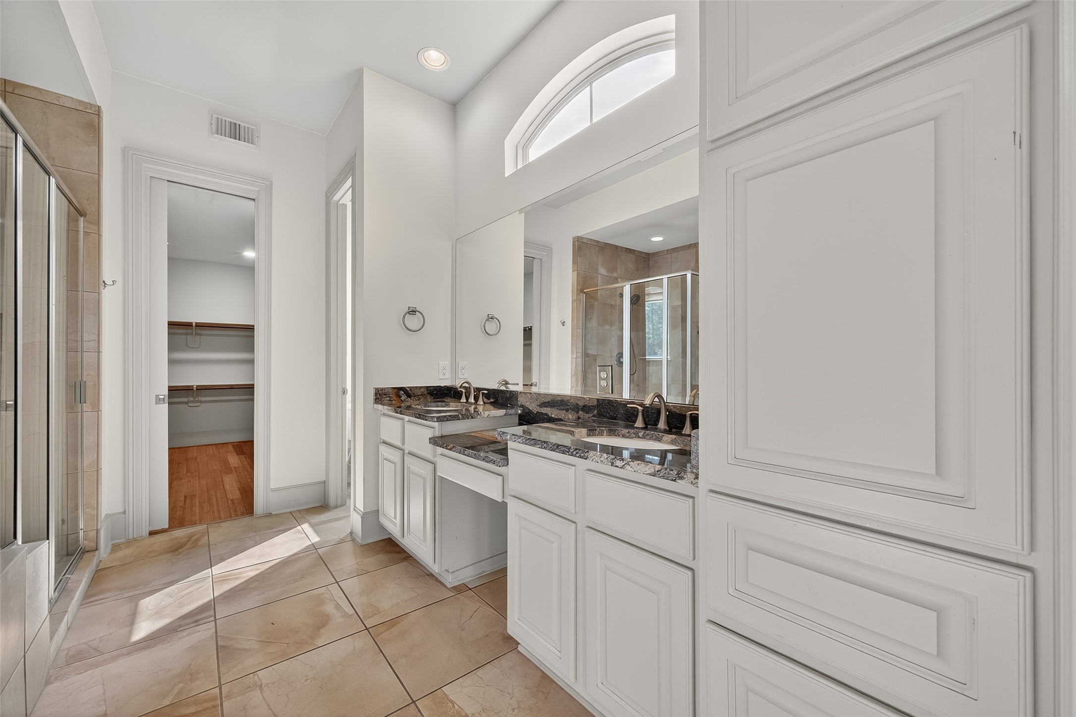 931 West 23rd Street, Unit K Houston, TX 77008 - Photo 17 of 40 Primary bathroom has double vanities with granite countertops, make-up vanity, tile flooring, transom window, recessed lights, and separate water closet.
