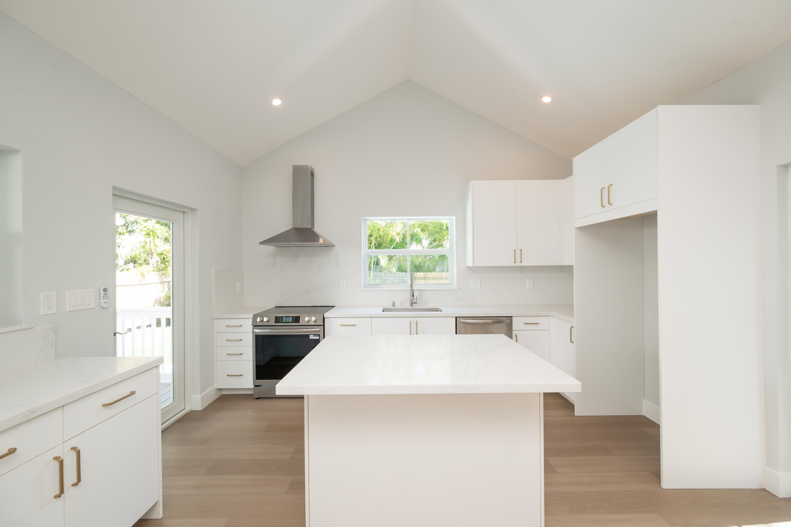 1315 William Street Key West, FL 33040 - Photo 17 of 26 a kitchen with a stove a sink a refrigerator and white cabinets with wooden floor