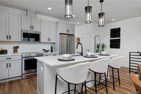 a kitchen with stainless steel appliances kitchen island granite countertop a table chairs microwave and cabinets