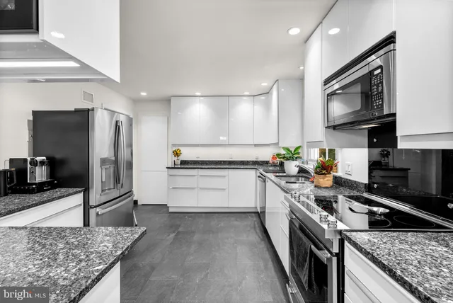 a large kitchen with stainless steel appliances granite countertop a stove refrigerator and a sink