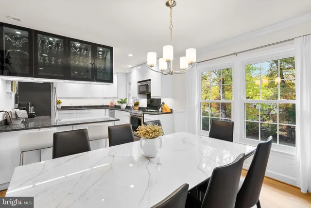 a kitchen with stainless steel appliances kitchen island granite countertop a dining table chairs and white cabinets