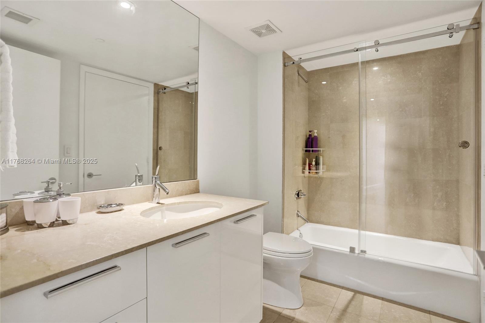 400 Alton Road, Unit 911 Miami Beach, FL 33139 - Photo 15 of 24 a bathroom with a double vanity sink toilet mirror and shower