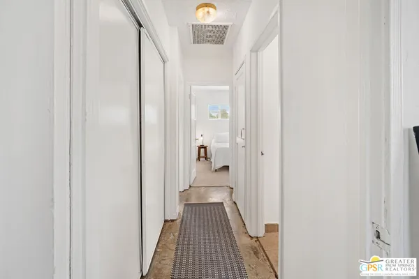 a view of a hallway with wooden floor and a bathroom