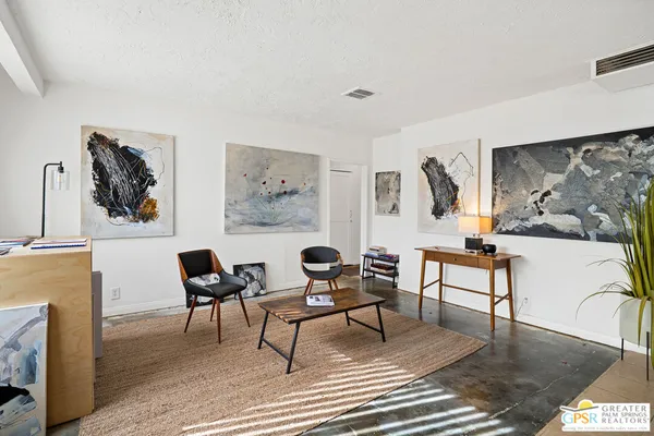a living room with furniture and paintings on the wall