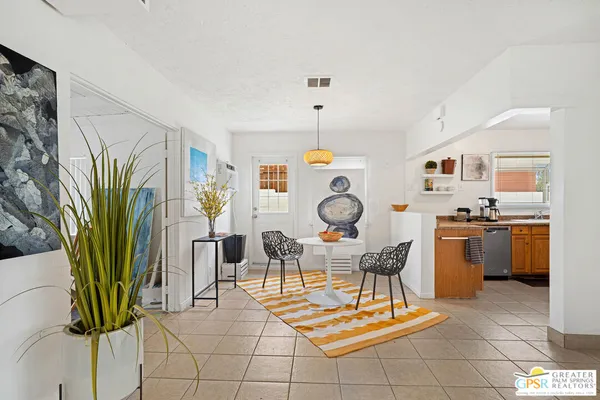 a dining room filled a chandelier and kitchen view
