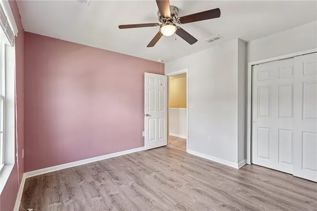 an empty room with wooden floor fan and windows