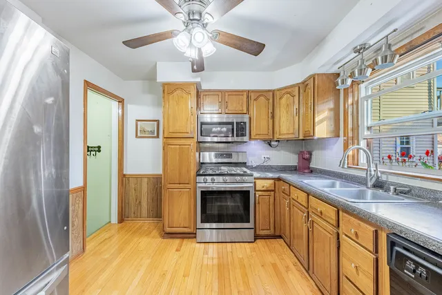 a kitchen with stainless steel appliances granite countertop a sink cabinets and a wooden floor