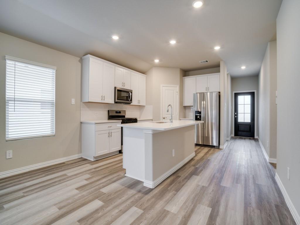 808 Tidal Drive McKinney, TX 75071 - Photo 8 of 26 a kitchen with white cabinets and stainless steel appliances