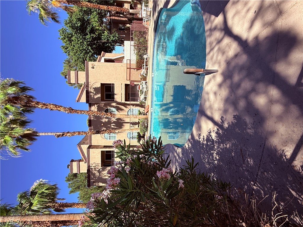 9325 West Desert Inn Road, Unit 260 Las Vegas, NV 89117 - Photo 31 of 42 A refreshing pool awaits, nestled amidst tropical landscaping with palm trees.