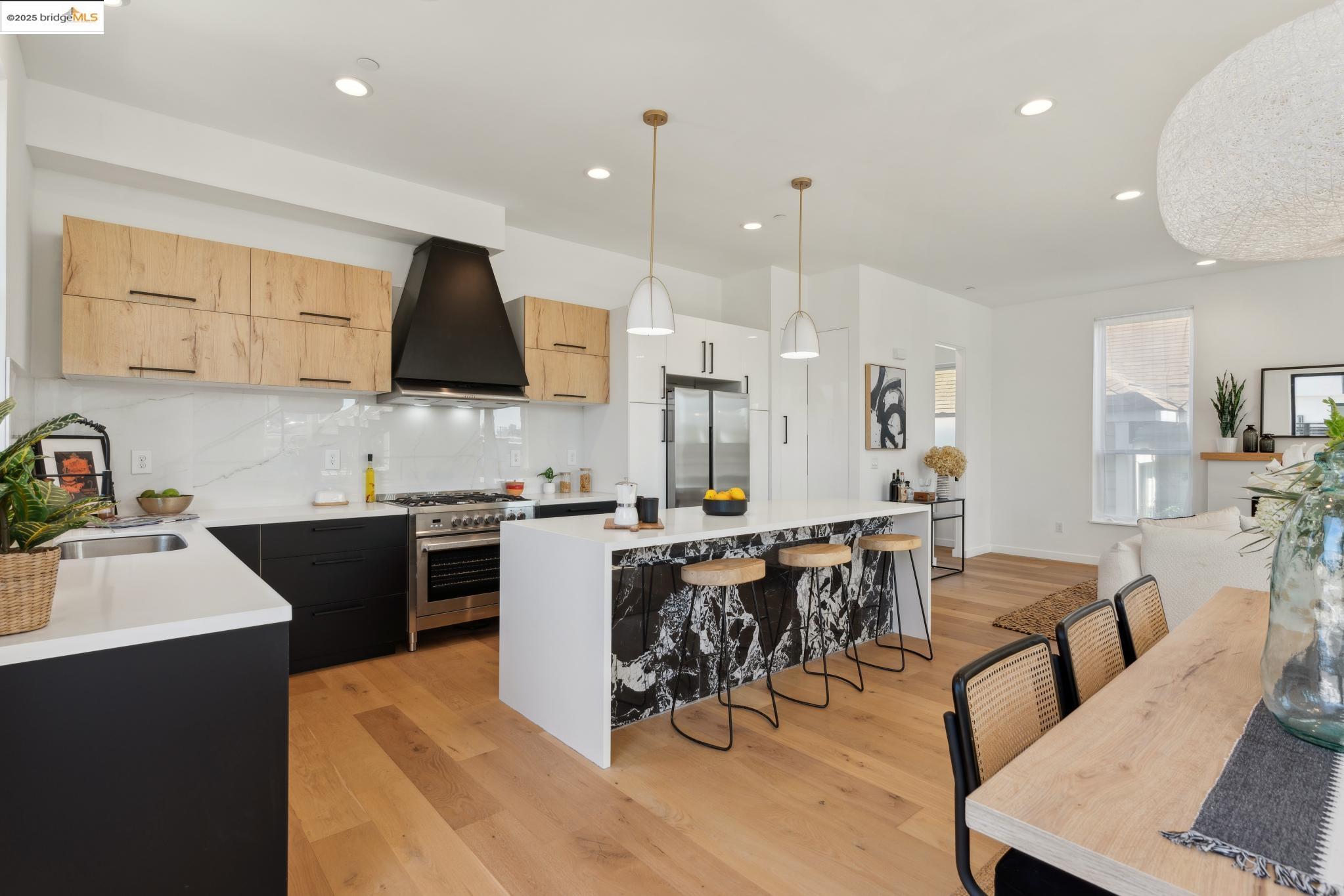 a kitchen with stainless steel appliances kitchen island granite countertop a sink a stove a dining table and chairs