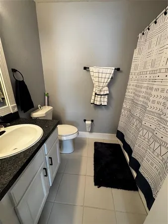 a bathroom with a granite countertop sink and a toilet