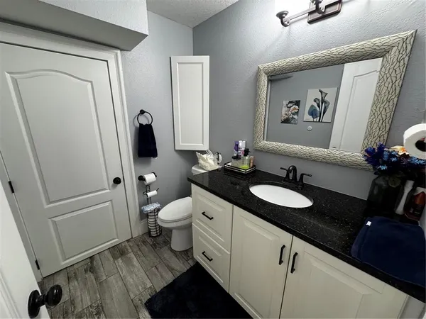 a bathroom with a granite countertop sink toilet and a mirror