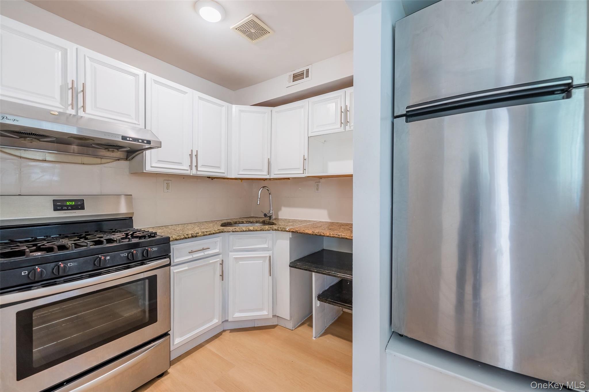 102-23 43rd Avenue, Unit 1B Queens, NY 11368 - Photo 5 of 18 a kitchen with stainless steel appliances granite countertop a stove a refrigerator and a microwave