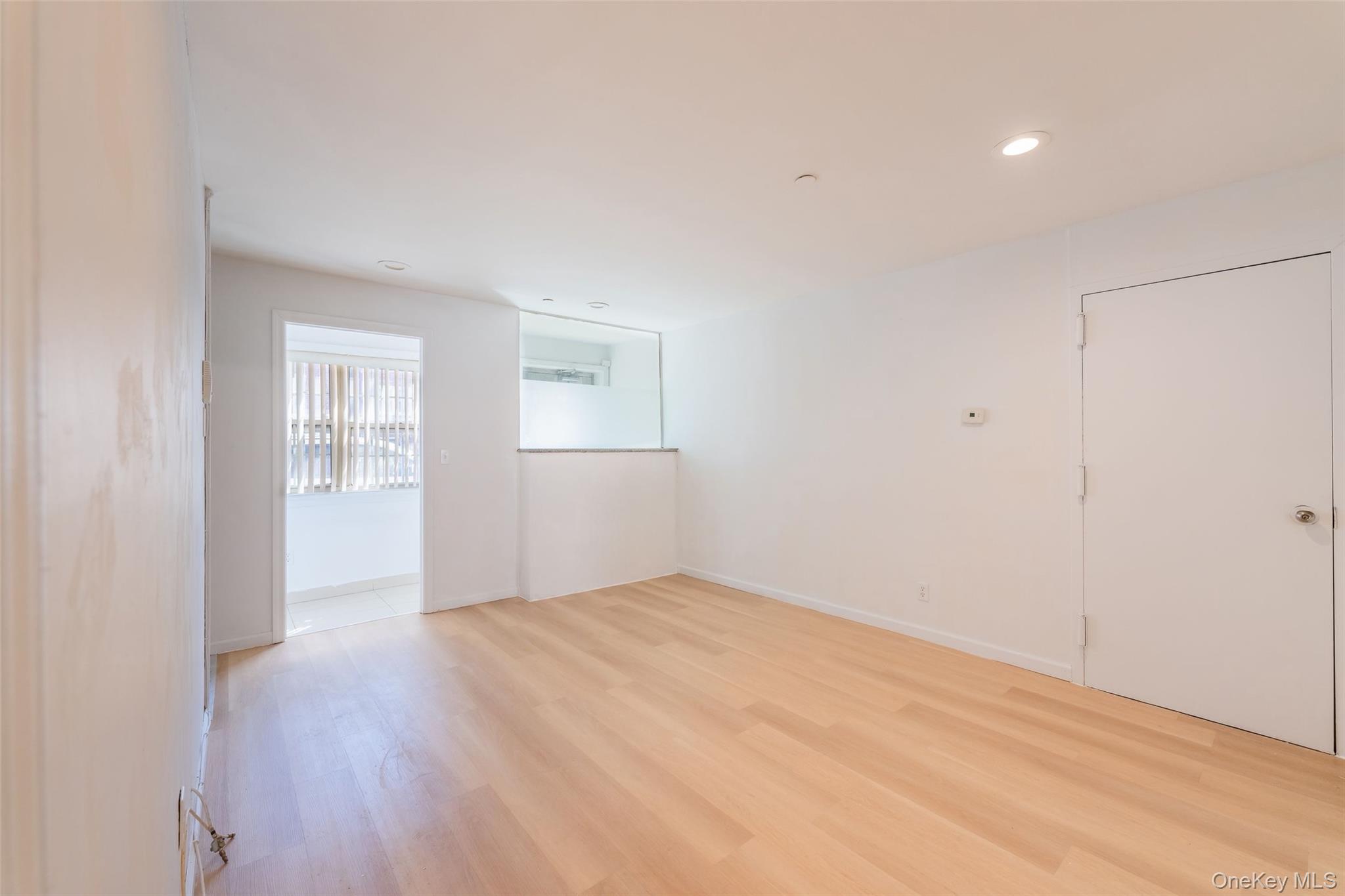 102-23 43rd Avenue, Unit 1B Queens, NY 11368 - Photo 7 of 18 a view of an empty room with wooden floor and a window