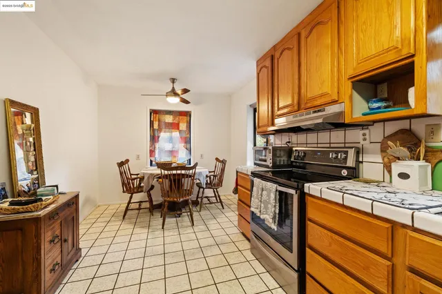a kitchen with stainless steel appliances granite countertop a stove top oven a sink a dining table and chairs