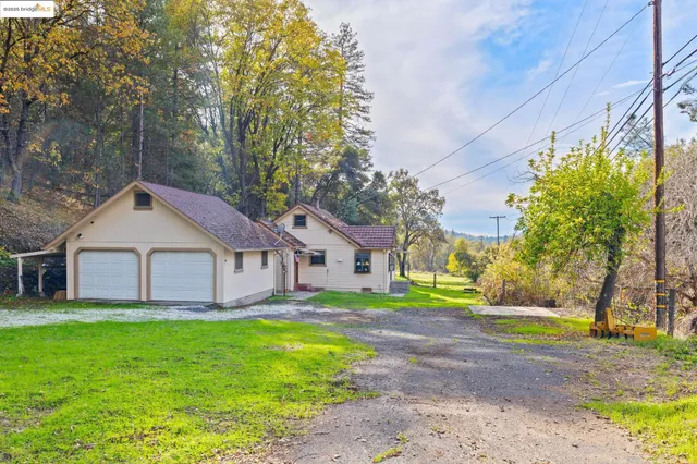a view of a house with a big yard and large trees