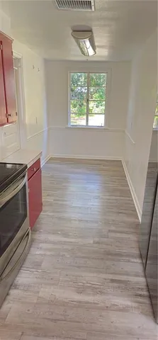 an empty room with wooden floor cabinet and windows