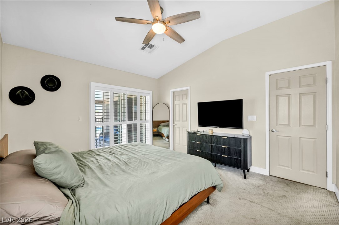 1234 Sunfire Street Henderson, NV 89014 - Photo 14 of 40 A well-lit bedroom featuring vaulted ceilings and direct outdoor access through sliding glass doors.