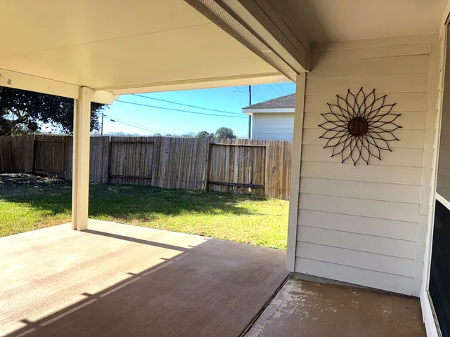 a view of a backyard with table and chairs with wooden fence and plants
